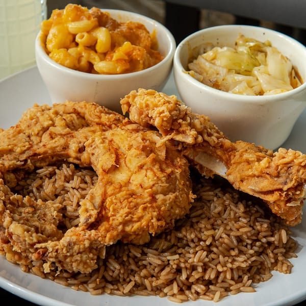 Crispy fried chicken and rice with sides of macaroni and cheese and cabbage.